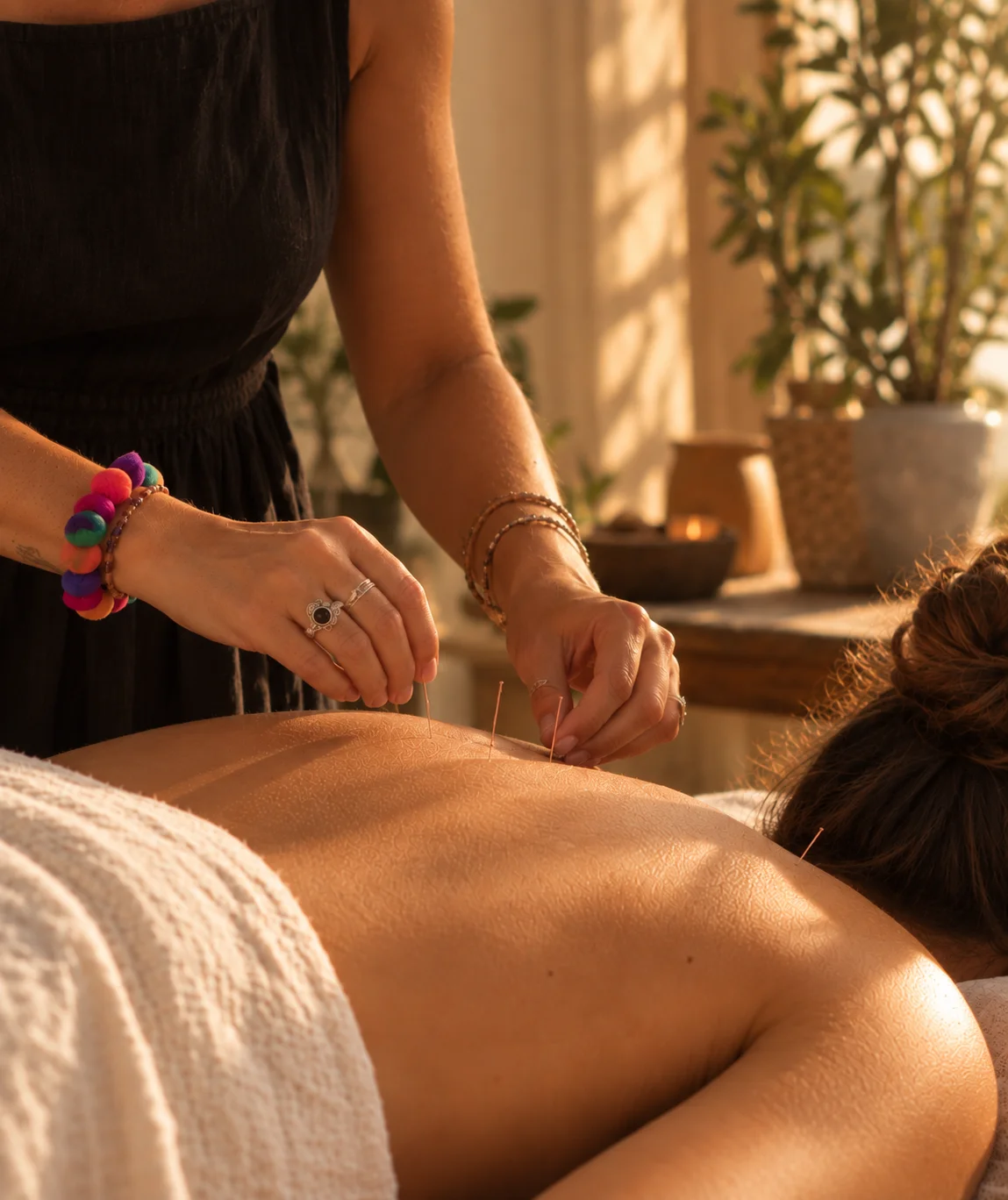 Détail de mains posant des aiguilles d’acupuncture sur le dos, dans une lumière naturelle chaleureuse