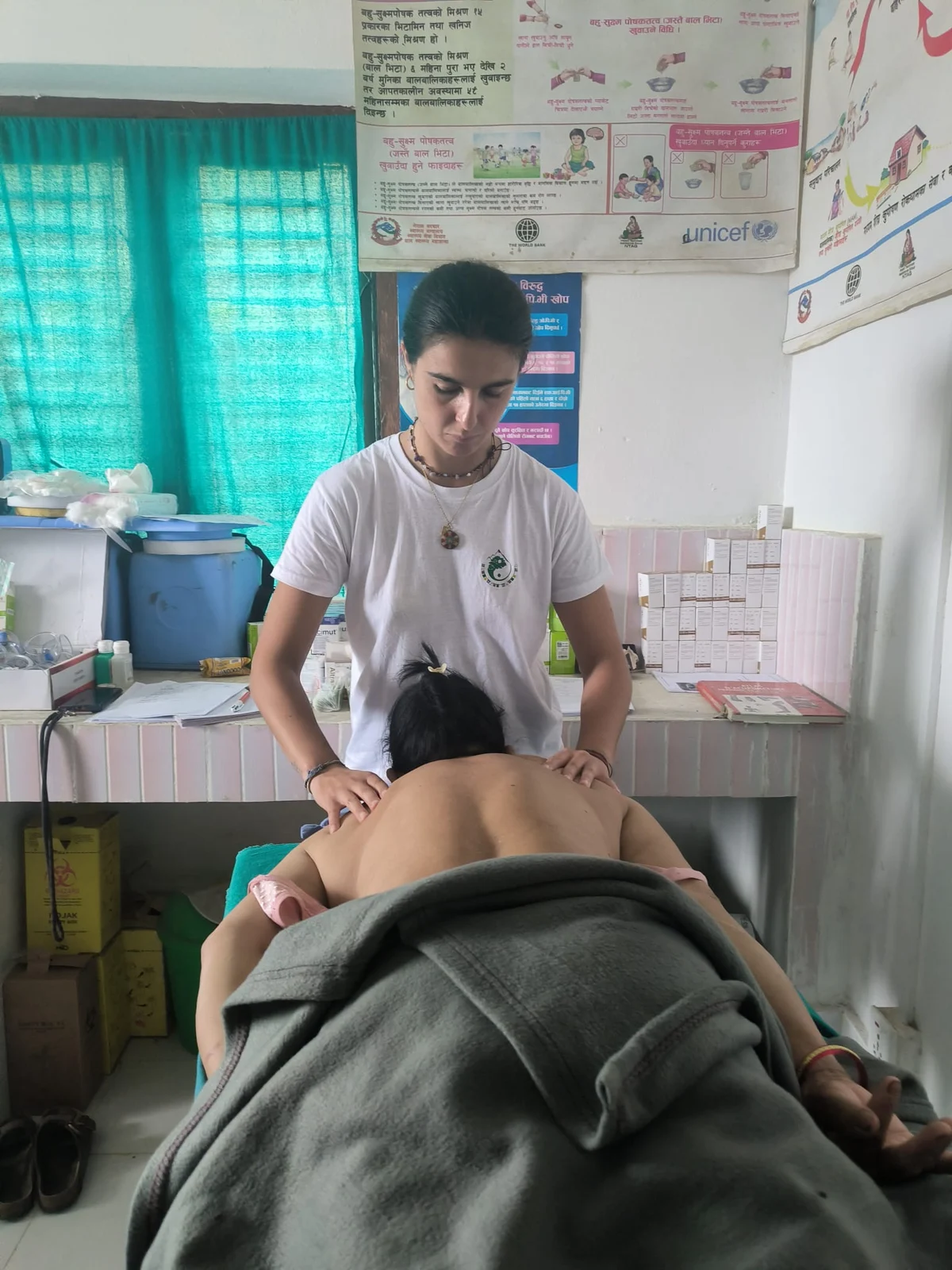 Lauriane en pratique, les mains sur le dos d’une personne allongée dans un centre de soins au Népal