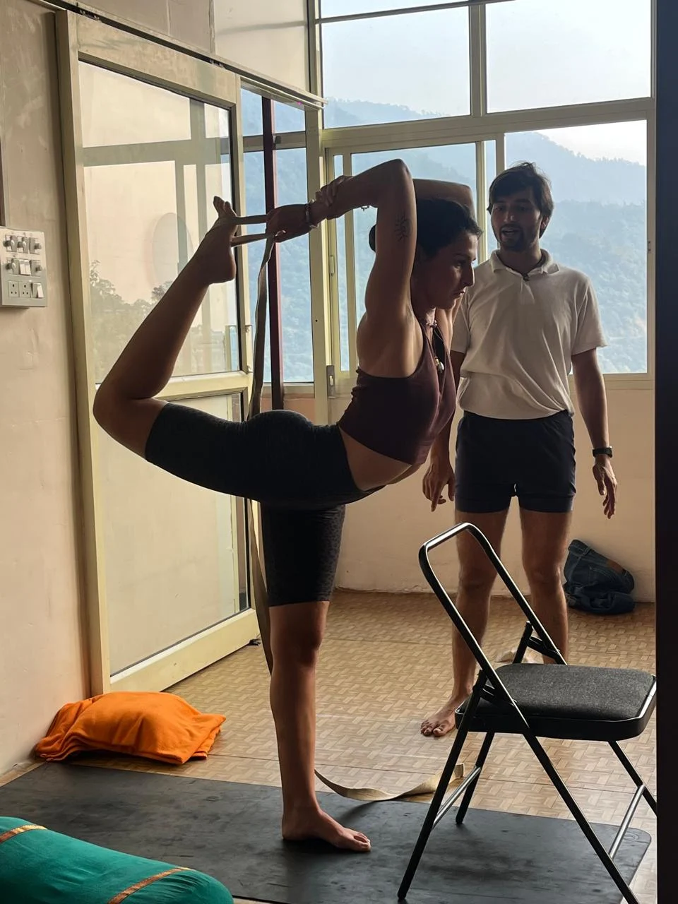 Lauriane pratiquant une posture de yoga avec une sangle, accompagnée par un enseignant en Inde