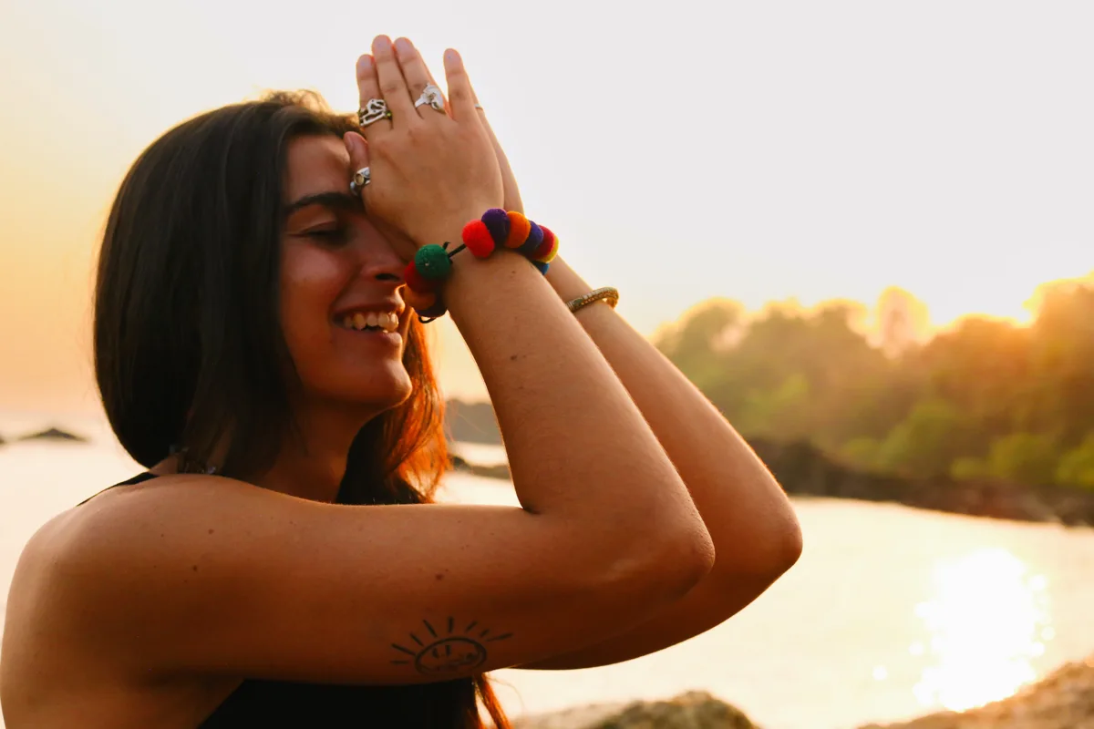 Lauriane au bord de la mer, les mains près du visage dans la lumière du coucher de soleil